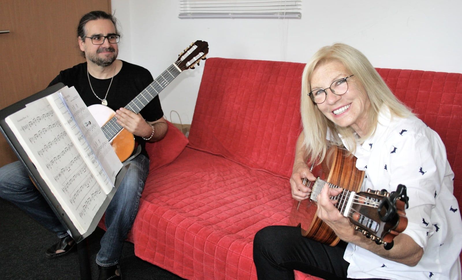 Gitarrenlehrer und Schülerin spielen gemeinsam Gitarre