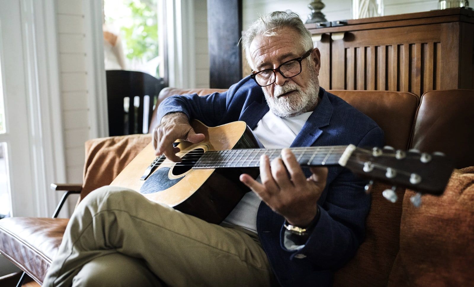 Älterer Herr spielt Gitarre im Sessel